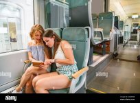 dos-chicas-jovenes-sentadas-en-tren-moderno-y-discutiendo-algo-2cd85gb.jpg