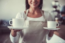 77846010-retrato-de-una-niña-feliz-barista-que-tiene-dos-tazas-de-café-para-los-visitantes-en-...jpg